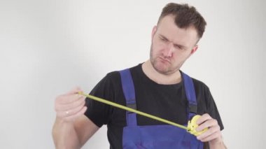 Üniformalı yakışıklı bir erkek müteahhit cebinden çıkar ve aletlerine bakar.