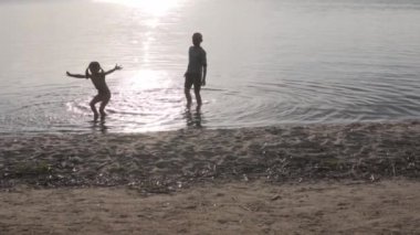 Çocuklar gün batımında gölde suda oynuyorlar, güzel gün batımı ışığı.