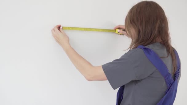 Стомлена жінка - художник перевіряє стіну перед малюванням. — стокове відео