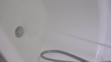 Musluk suyu banyoyu doldurur, kadınlar banyo için pembe tuz döker..