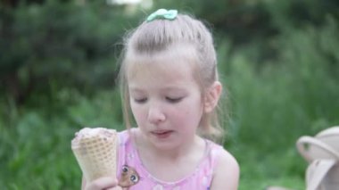 Küçük tatlı bir kız yazın parkta waffle bardağında çikolatalı dondurma yiyor.