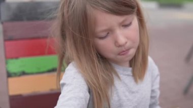 Küçük bir kız caddedeki kafede tek başına patates kızartması yiyor.