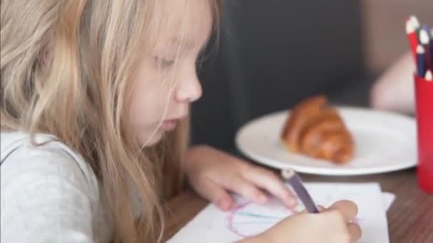 Una niña pequeña pinta un cuadro en un café durante el almuerzo — Vídeo de stock