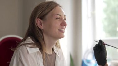 Bir kadın evdeki bir müşteri tarafından kaşlarını siyaha boyuyor.