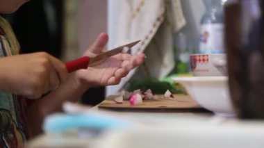 Bir kadın kesim tahtasıyla turp kesiyor, yakın plan.