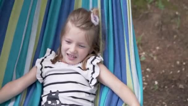 Primo piano, carina bambina si trova su un'amaca in estate nel parco — Video Stock