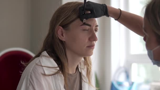 Une femme sur la correction des sourcils dans un salon de beauté, gros plan — Video