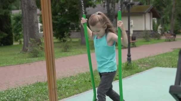 Tournage au ralenti, une belle petite fille monte une balançoire en été dans le parc seul — Video