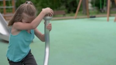 Küçük bir kız yazın oyun bahçesinde oynar