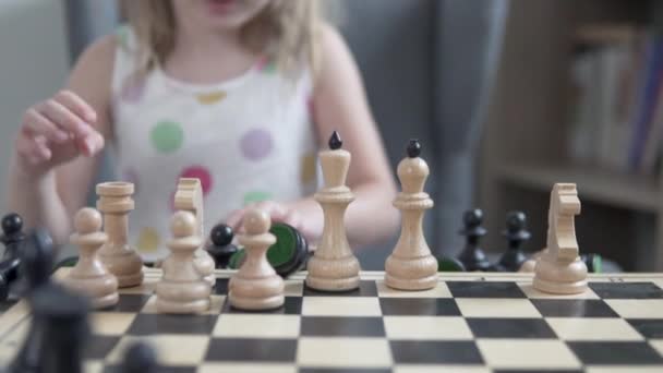 Το κοριτσάκι βάζει πιόνια σκακιού στον πίνακα, η εστίαση στις φιγούρες, το παιδί είναι θολό. — Αρχείο Βίντεο