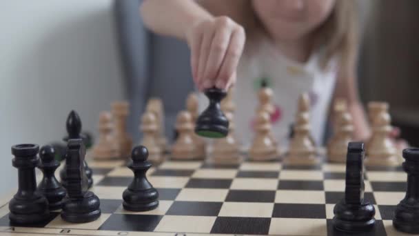 한 어린 소녀 가집에 있는 체스 판에 검은 조각들을 놓는다 — 비디오