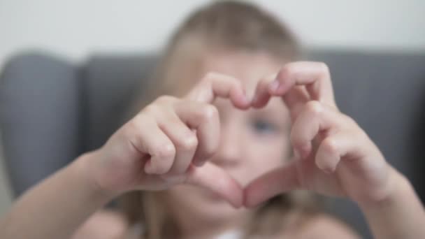 Egy aranyos kislány megmutatja a szívét a kezéből. — Stock videók