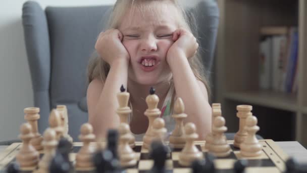 Lustiges kleines Mädchen hat genug vom Schachspielen. — Stockvideo