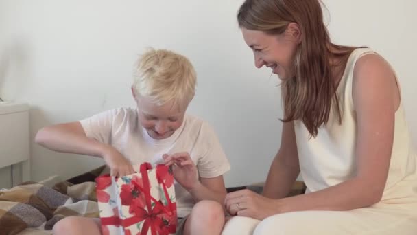 Mamá le da a su hijo un colegial un regalo en un hermoso paquete — Vídeos de Stock