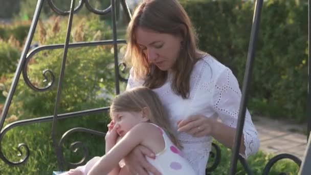 En vacker mor och liten dotter rida en gunga tillsammans på sommaren i parken — Stockvideo
