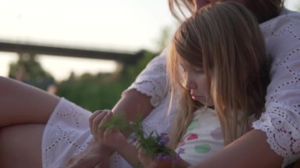 Maman étreint sa petite fille le soir dehors en été — Video