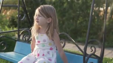 Küçük bir kız yazın salıncağa biner
