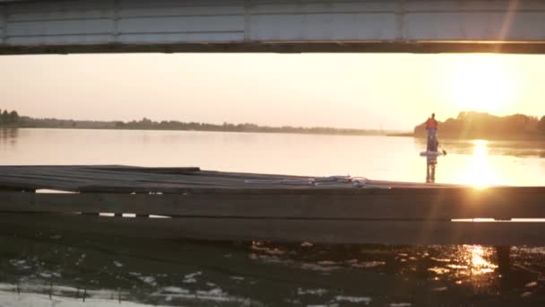 Un homme nage sur une planche SUP le long de la rivière au coucher du soleil — Video