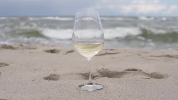 Una copa de vino blanco en la playa sobre el fondo de bueyes en el mar — Vídeos de Stock