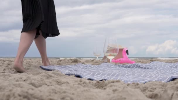 携帯電話を持った女性が海岸の毛布の上に座っている — ストック動画