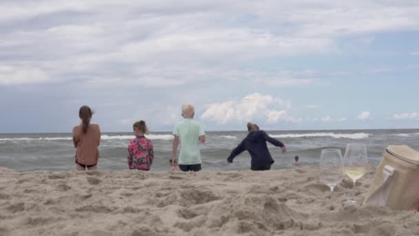 Les enfants regardent la mer turbulente dans les vagues en été sur la plage, la vue de l'arrière — Video