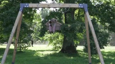 Neşeli küçük bir kız yazın parkta salıncak sürüyor.