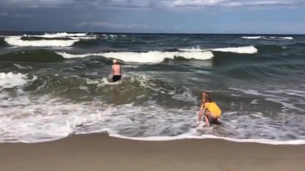 Les jeunes enfants pénètrent dans les mers pendant une tempête. — Video