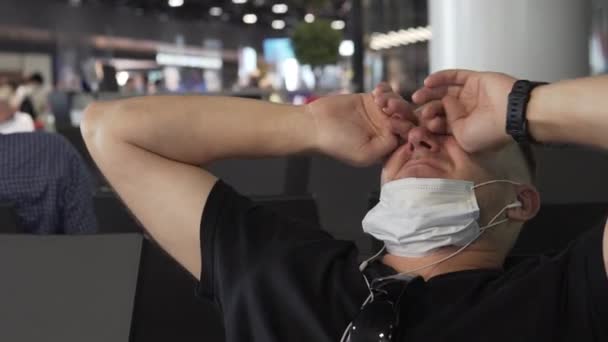 特写，一个戴着医疗面具的男人在机场醒来 — 图库视频影像