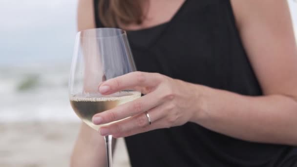 Close-up, slow-motion filmen, een vrouw die wijn drinkt uit een glas op het strand aan zee — Stockvideo