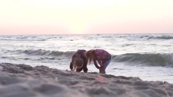 .Les filles deux sœurs jouent au bord de la mer au coucher du soleil en été — Video