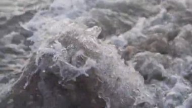 Denizde dalgalar ve taşlar, bir rupi planı, gün batımında yavaş çekim..