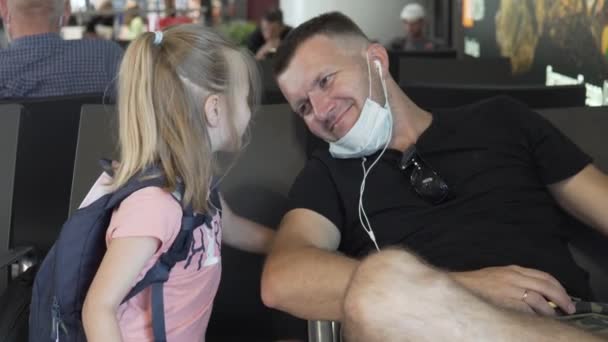 Un padre y una hija pequeña están esperando un avión en la sala de espera en el aeropuerto durante la pandemia de coronavirus — Vídeos de Stock