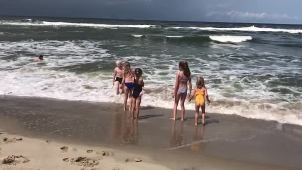 Latem dzieci pływają w morzu z falami. — Wideo stockowe