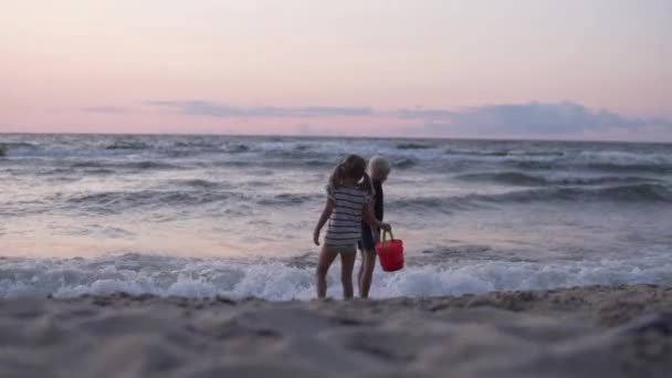 Dzieci bawią się na piaszczystej plaży o zachodzie słońca w lecie — Wideo stockowe