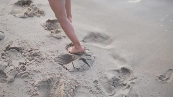 Close-up, the little girls legs leave traces on the sand — Stock Video