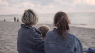 Çam ağaçlarının manzarası, anne ve kızları sahilde sigara içecekler.