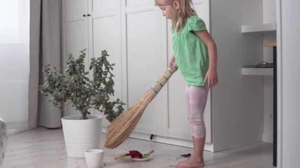 Mała dziewczynka zamiata podłogi domu miotłą.. — Wideo stockowe