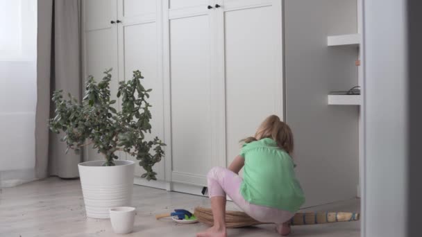 Ένα χαριτωμένο κοριτσάκι καθαρίζει το δωμάτιο του σπιτιού. — Αρχείο Βίντεο