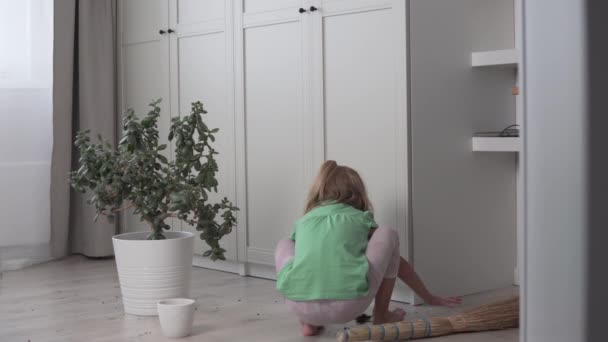 Una niña recoge la tierra del laminado. Lindo bebé elimina la basura del suelo de la casa — Vídeo de stock