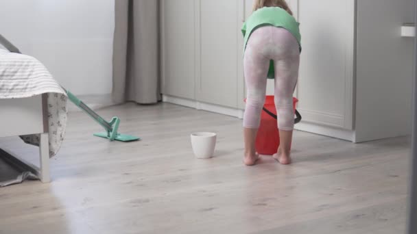 Ein süßes kleines Mädchen wäscht die Böden des Hauses — Stockvideo