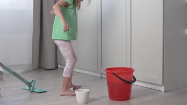 Küçük bir kız dairede yerleri yıkıyor.