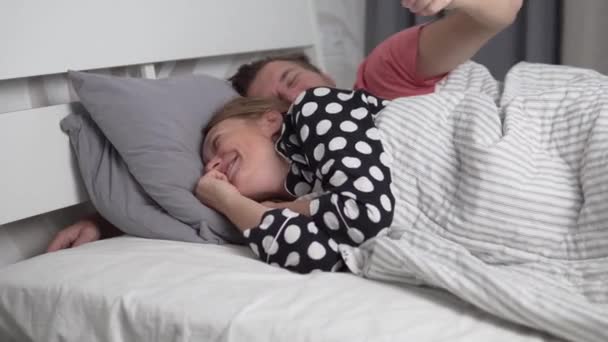 Una pareja enamorada se despierta por la mañana en la cama, un hombre abraza a su amada mujer — Vídeo de stock