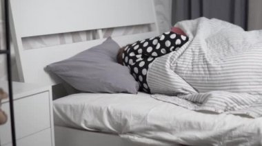 Uykulu bir kadın ve bir erkek sabahları yatakta dönüp duruyorlar.