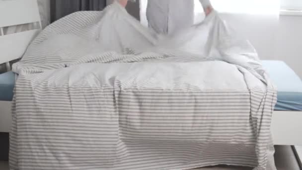 ผู้หญิงคนหนึ่งกระจายผ้าปูที่นอนที่สะอาดบนเตียง — วีดีโอสต็อก