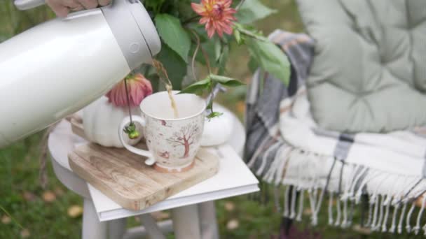Женская рука наливает чай в чашку из термоса в красивом осеннем парке. — стоковое видео