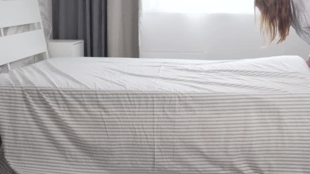 Домогосподарка кладе чистий лист на матрац на ліжко вдома — стокове відео