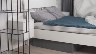 Bir kadın sabah evde bir yatak yapar. Ev hanımı yatağı temizler, yatak örtüsünü serer.