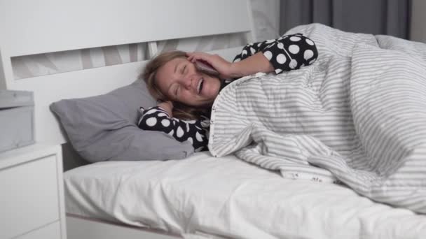 Seorang wanita berbicara di telepon di pagi hari di tempat tidur — Stok Video