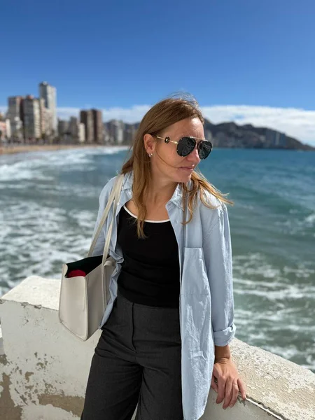 Benidorm, İspanya. Deniz kenarındaki gezinti alanında duran güzel bayan turist.