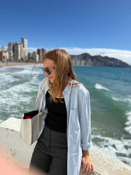 Benidorm, İspanya. Gökdelenleri ve arka planında deniz olan iş kadını, dikey fotoğraf